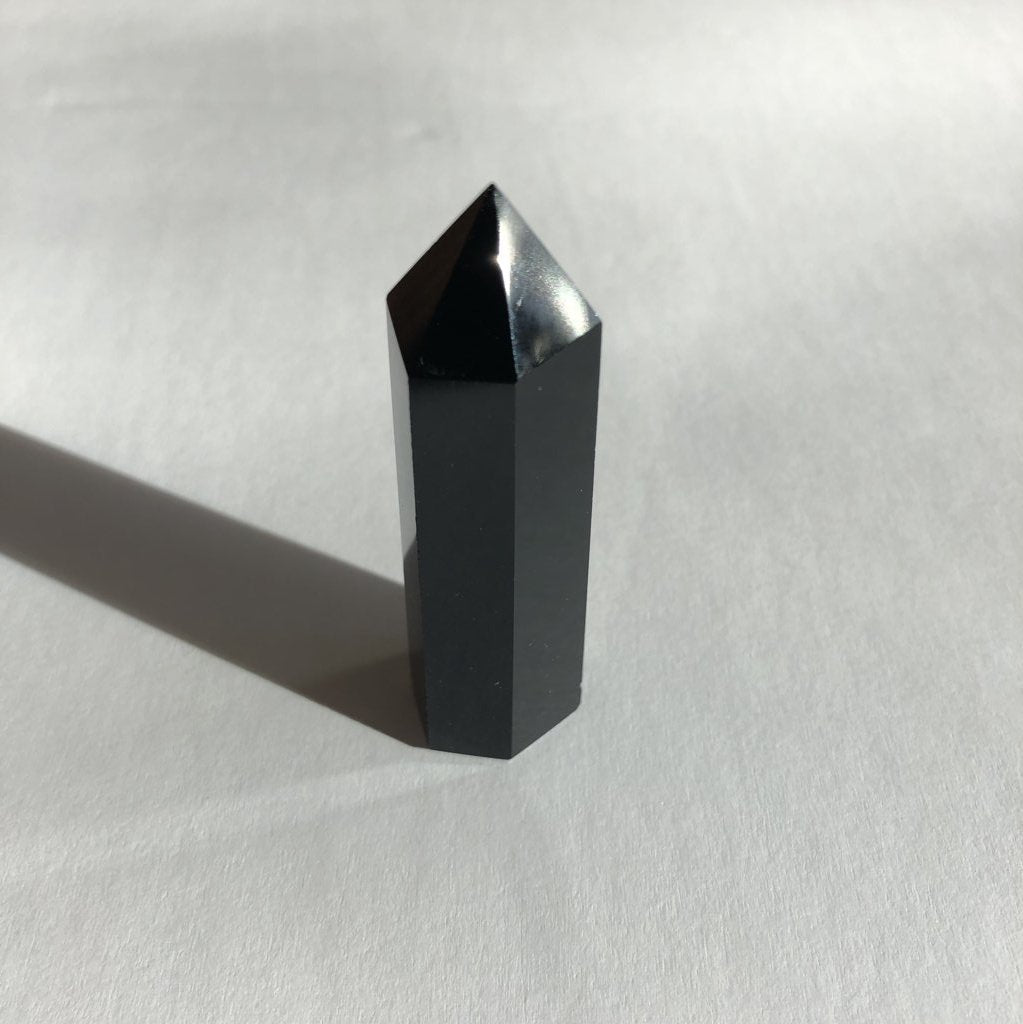 Obsidian Point crystal on white background with shadow