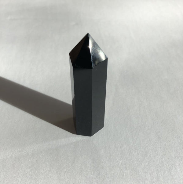 Obsidian Point crystal on white background with shadow