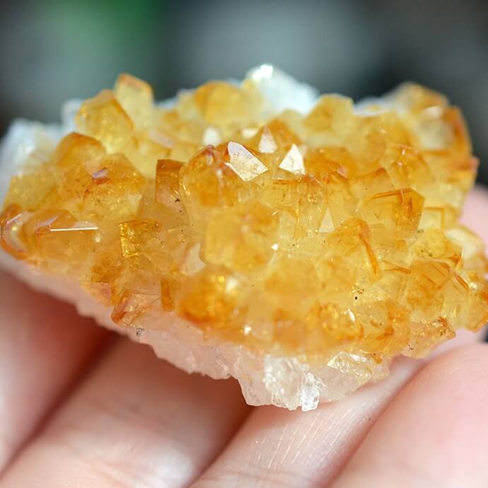 citrine crystal placed on top of fingertips close up view