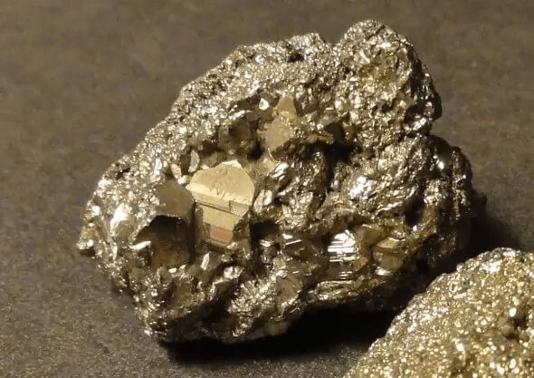 raw pyrite rock placed on a concrete surface close up view