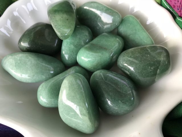 many pieces of different shades of green pebbles placed on a white plate