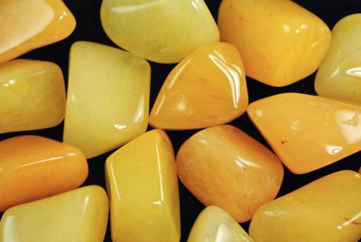 pieces of polished smooth yellow pebbles on a black background top view