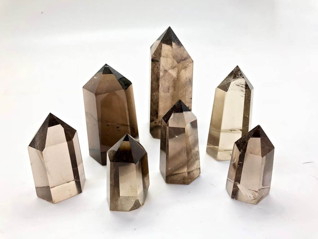 seven pieces of smoky prism crystals on a white background