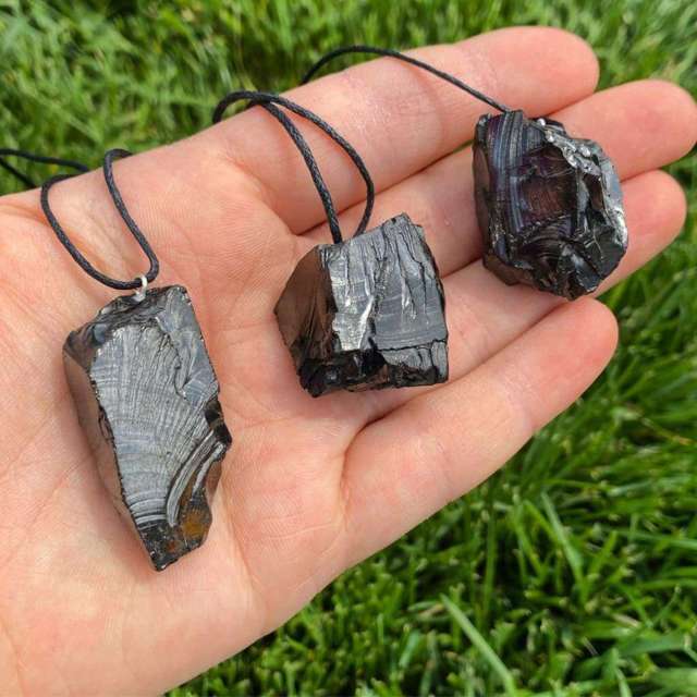 hand holding three necklaces with black crystal rock pendants