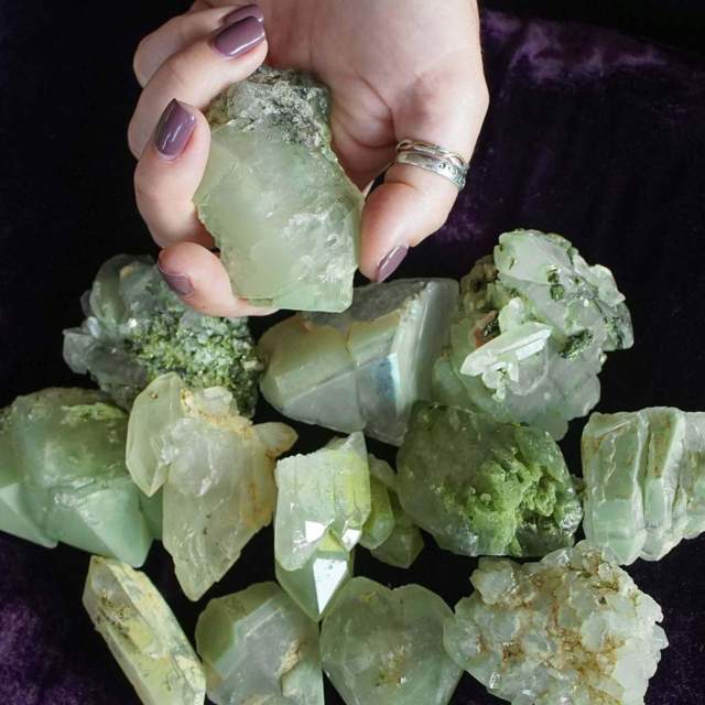 hand holding raw green crystal rock and other pieces below