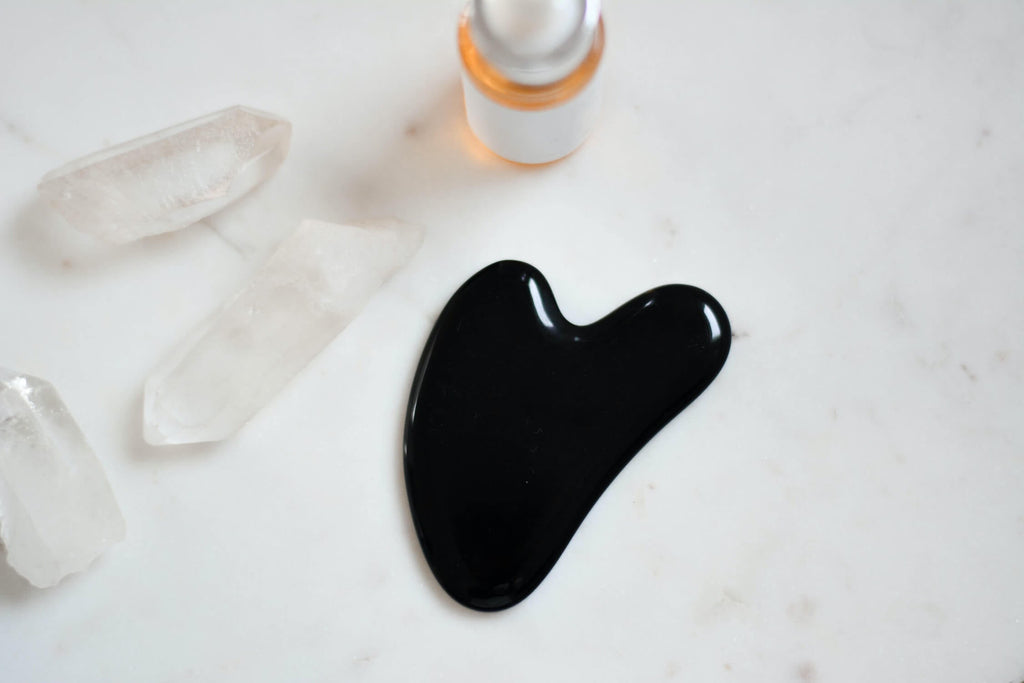 black gua sha beside three pieces of clear crystals