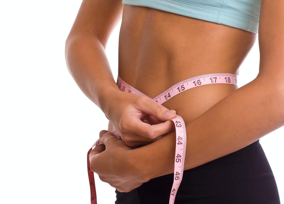 woman wear blue top and black pants wrapping tape measure around her wait 