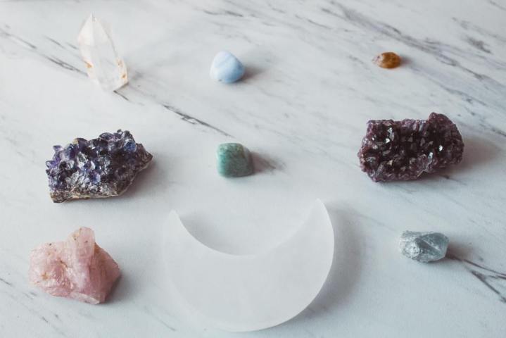 different types sizes colors of raw and polished crystal rocks on a white marble surface