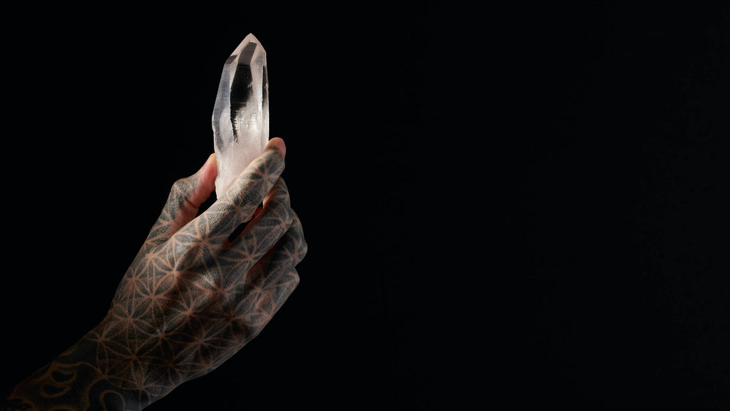 tattooed hand holding white clear crystal black background