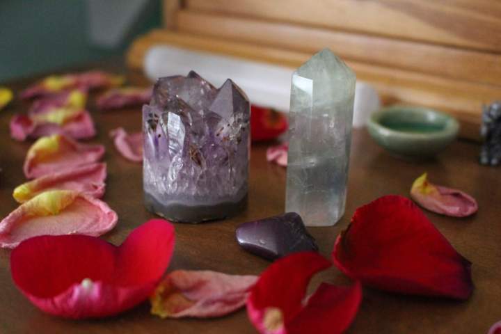 purple and greenish crystals surrounded by rose petals