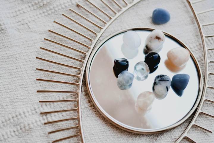 different color and types of small crystals and stones placed on a mirror