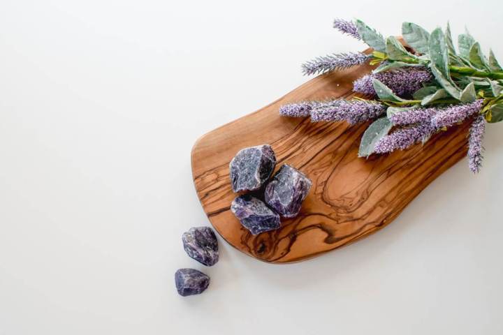 pieces of purple unpolished rocks lavender flowers on a slab of wooden surface