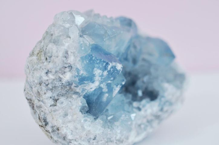 blue raw crystal rock pink background close up view