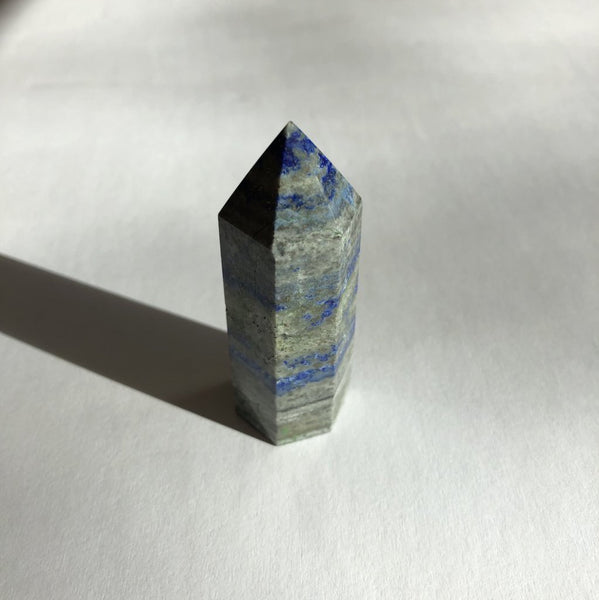 Lapis Lazuli Point crystal on white background with shadow